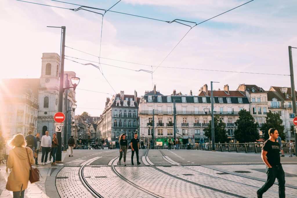 pexels-photo-2464435-2464435 People walking across a sunny tramway intersection in a historic European city.
